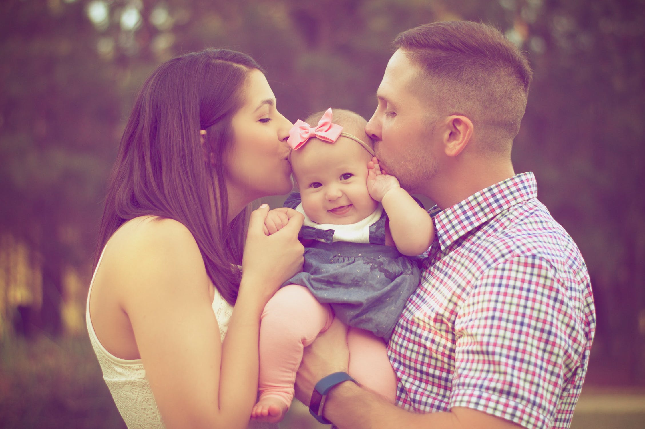 Family Young couple kissing their baby - how much insurance will keep your family safe? MBG Insurance