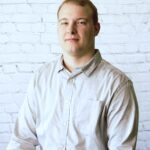 Photo of Insurance Agent Tyler Hunter in front of white brick background.